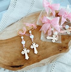 three wooden crosses are sitting on a piece of wood next to some pink bows and beads