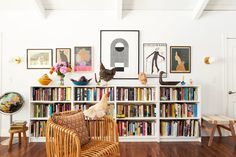 a living room filled with lots of furniture and bookshelves covered in pictures on the wall