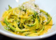 a white bowl filled with pasta covered in cheese and broccoli florets