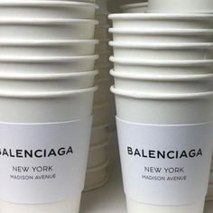 several white cups stacked on top of each other in front of a wall with the words baleinicaa written on them