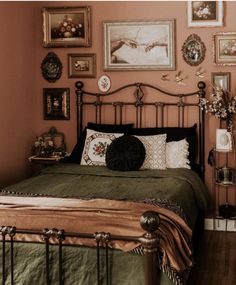 a bed in a bedroom with pink walls and pictures on the wall above it's headboard