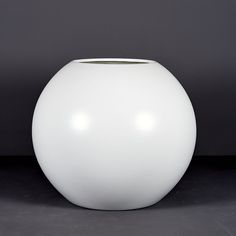 a large white vase sitting on top of a black floor next to a gray wall