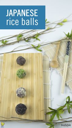 japanese rice balls are arranged on a bamboo mat with chopsticks and green leaves