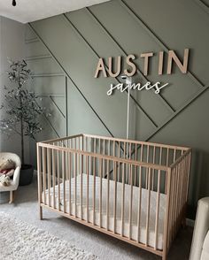 a baby's crib in front of a wall with the name austin on it