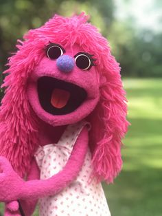 a pink stuffed animal with big eyes holding a tennis racquet in its hand