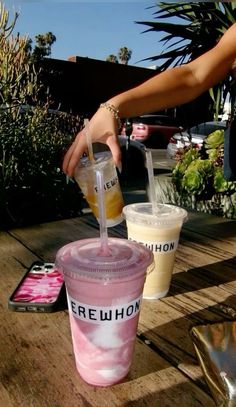 a person is pouring something into a cup on a picnic table with other drinks in the background