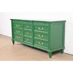 a green dresser with gold handles and drawers