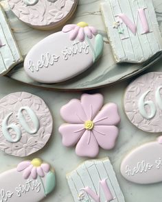 decorated cookies are displayed on a plate with the number six and two - dimensional flowers