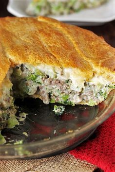 a meat and vegetable pie is cut in half on a glass plate with a red napkin