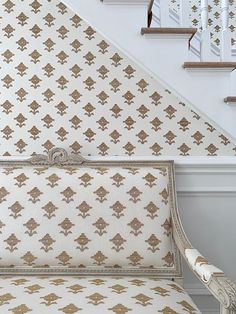 a white and gold patterned bench in front of a stair case next to a banister