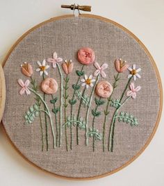 a close up of a embroidery on a wooden hoop with flowers in the middle and behind it