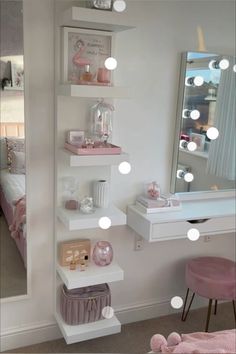 a white shelf filled with lots of items next to a mirror and pink stools