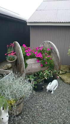 a garden filled with lots of potted plants next to a wooden bench covered in flowers