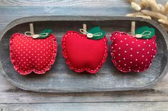 three red apples sitting on top of a wooden tray