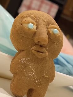 a close up of a cookie shaped like a teddy bear with blue eyes and mouth