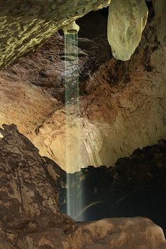 there is a waterfall in the middle of this cave with rocks and water flowing from it