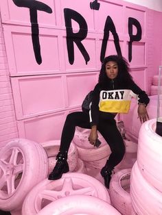 a woman sitting on top of pink tires in front of a sign that says trap