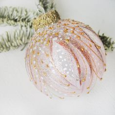 a pink ornament sitting on top of a white table next to a christmas tree