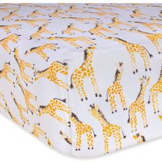 a white and yellow bed sheet with giraffes printed on the bottom half