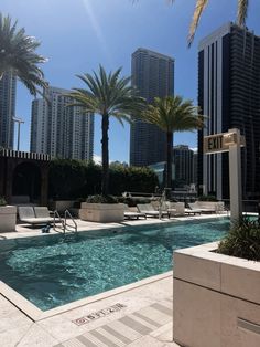 an outdoor swimming pool with lounge chairs and palm trees