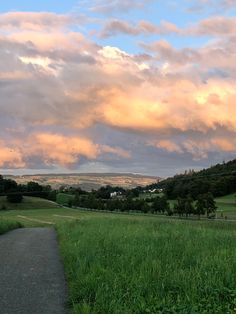 an empty road in the middle of a grassy field