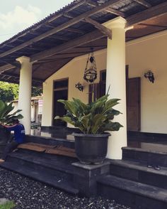 a woman sitting on the front steps of a house with potted plants in front