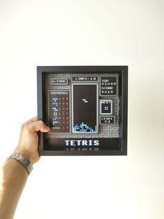 a person holding up a video game screen with the words tetris on it