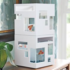 a white model house with fish in it on a table next to a potted plant