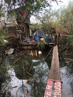 there is a boat that is in the water near a tree and shack on stilts