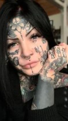 a woman with lots of tattoos on her face and arm is posing for the camera