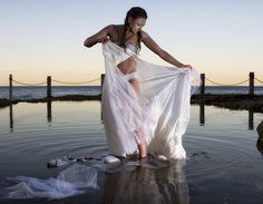 a woman in a white dress is standing in the water