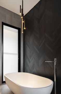 a large white bath tub sitting in a bathroom next to a tall wall mounted light