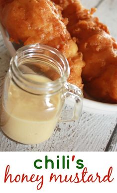 there are some fried food in a bowl and a jar with sauce on the side