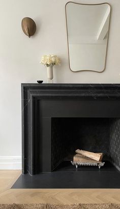 a black fireplace with white flowers and a mirror on the wall in front of it