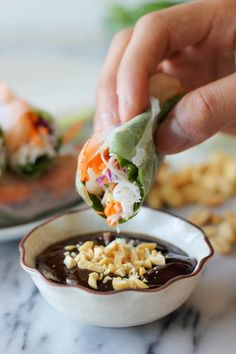 a person dipping some food into a bowl