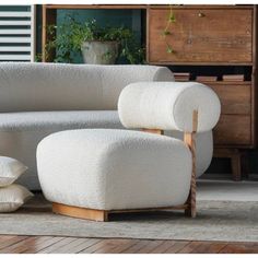 a white couch sitting on top of a wooden floor next to a chair and ottoman