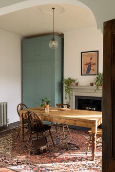 a dining room table and chairs in front of a blue door with an ornate rug on the floor