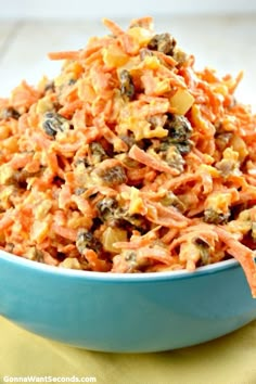 a blue bowl filled with carrot salad on top of a yellow napkin