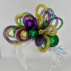 a purple, green and gold flower with glitters on it's headband