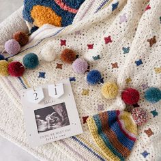 a crocheted blanket with pom - poms on it and a photo pinned to the side