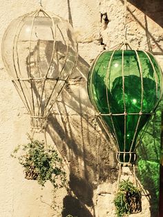 two green glass hot air balloons hanging on a wall next to a potted plant