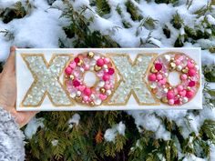 a person holding up a decorated box with the word xoxo spelled in it