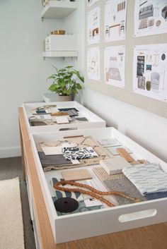 two drawers with pictures on the wall and a plant in vase next to each drawer