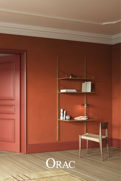 an orange room with a chair and shelf on the wall next to a red door