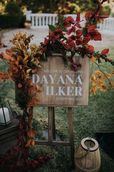 a wooden sign sitting on top of a lush green field next to flowers and trees