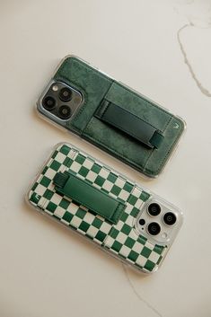 two cell phones sitting next to each other on top of a white table with green and white checkered cases