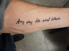 a person with a tattoo on their arm that says, any way the wind blows