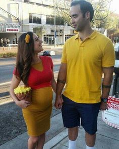 a man and woman dressed in costumes standing next to each other on the sidewalk holding hands