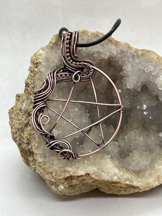 a wire wrapped pendant sitting on top of a rock