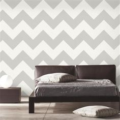 a bed sitting in front of a wall with a chevron pattern on it's side